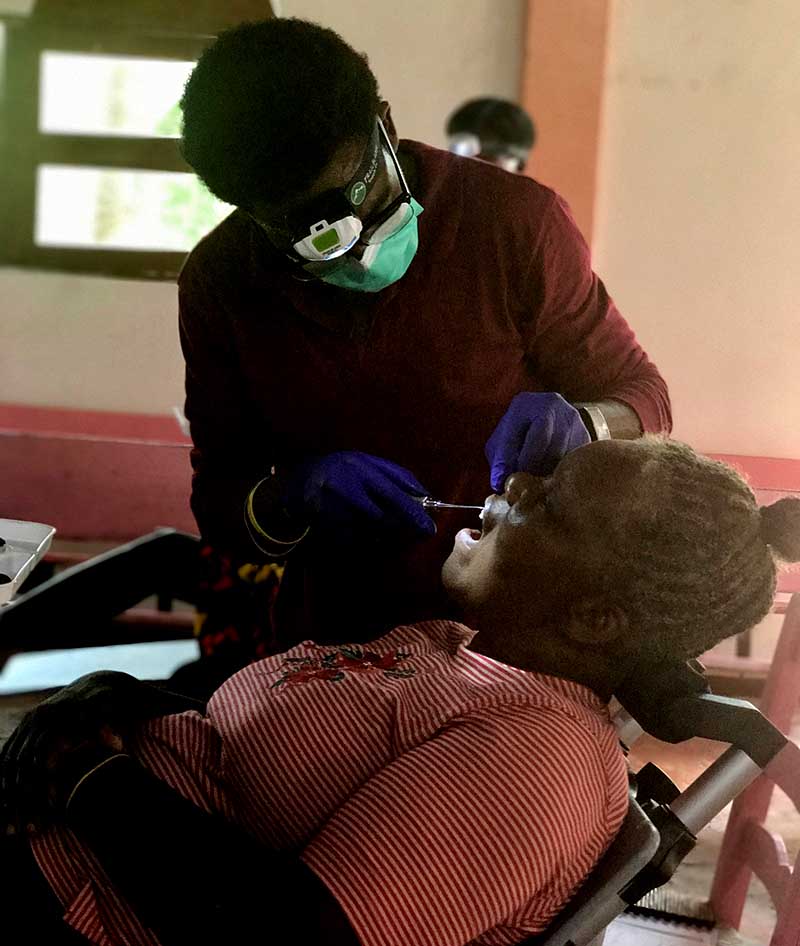 young dental trainee works on patient in Haiti